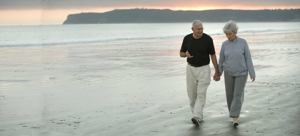 Senior husband and wife walking along the beach in California