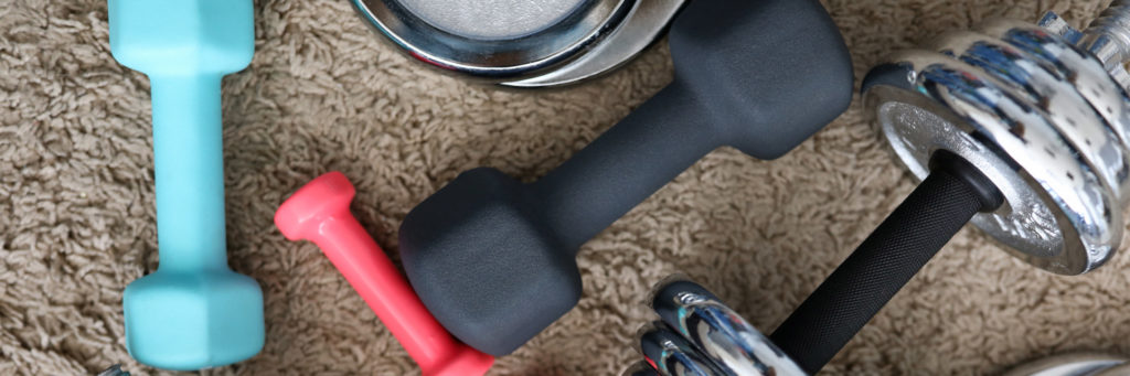 Pile of shiny chrome dumbbells disks lying around grip at home rug as domestic sport exercises during coronavirus quarantine period close-up