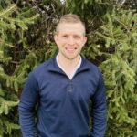 Smiling man in front of trees.