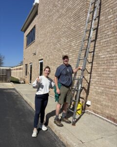 Two people by a ladder outside.